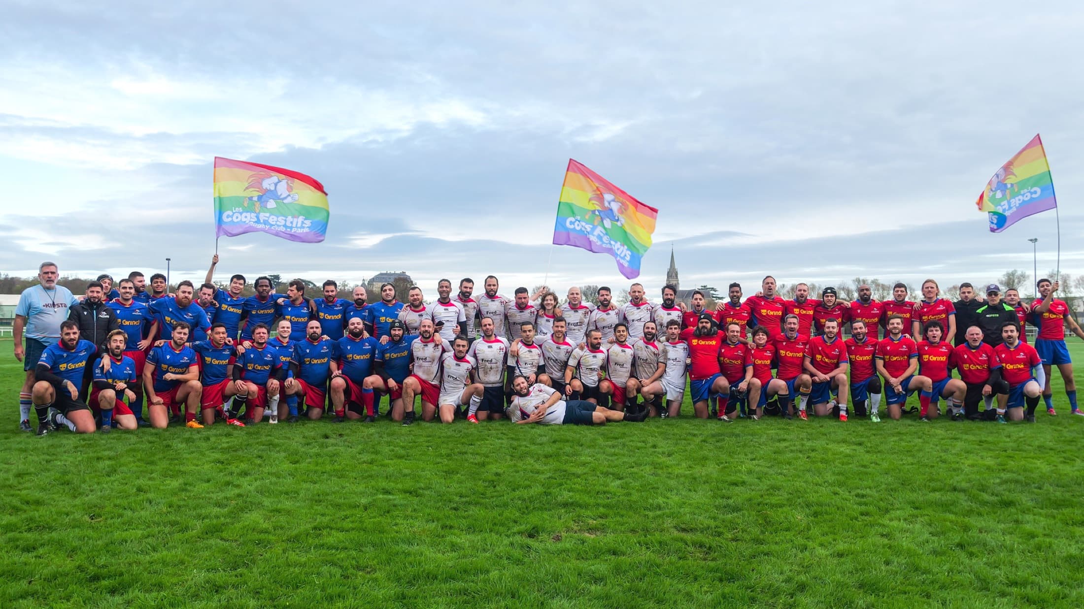 Photo d'équipe des Coqs Festifs avec drapeaux arc-en-ciel sur le terrain